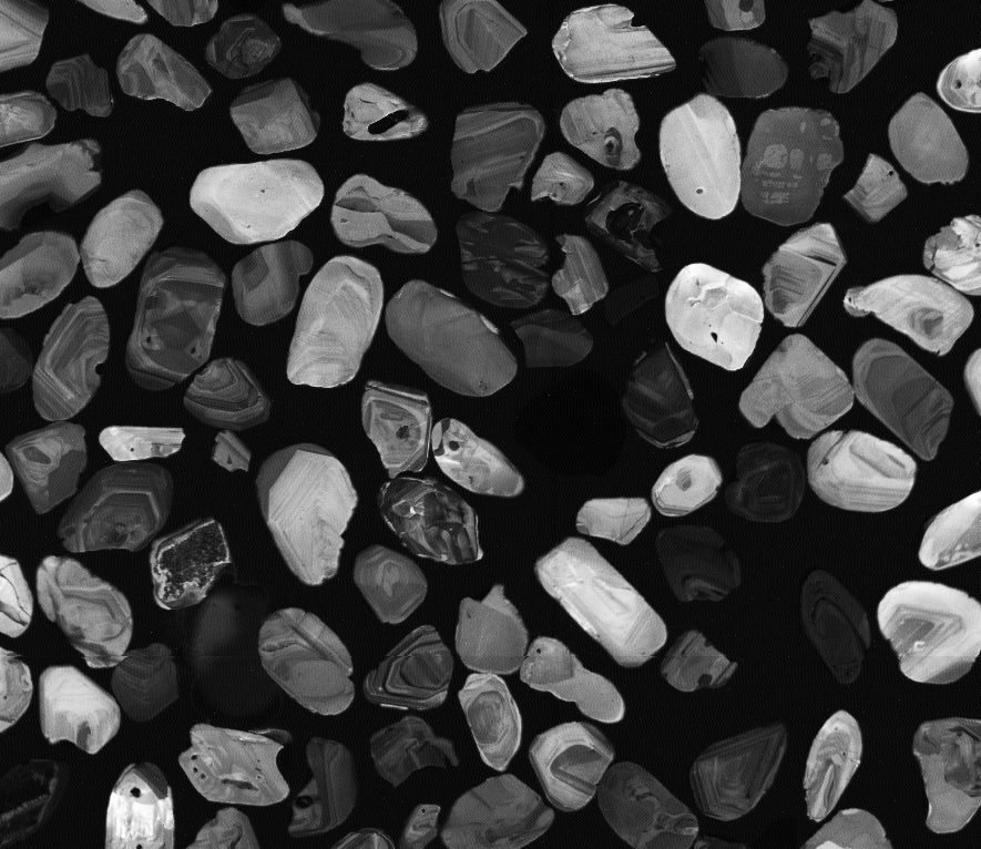 Scanning electron microscope image of zircon crystals. Each crystal is about 0.1 millimeters in size, which is roughly the thickness of a human hair, and records cosmogenic krypton as a geochemical time archive.