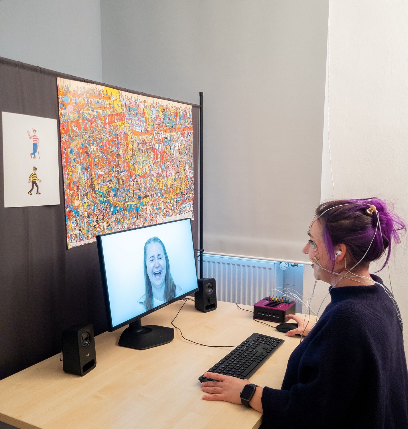 Test subject in the experiment: Electrodes on the skin measure the activity of the facial muscles. The colorful picture puzzle is intended to distract from the joke. Immediately after each joke, the test subject saw and heard a laughing person — a social stimulus that makes it difficult to suppress laughter.