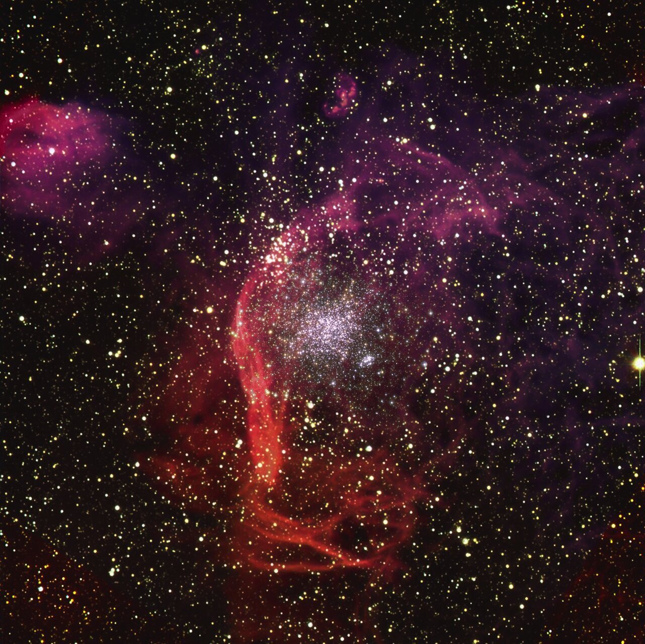 NGC1850 as seen with the Very Large Telescope and Hubble:  NGC1850, a cluster of thousands of stars roughly 160,000 light-years away in the Large Magellanic Cloud, a Milky Way neighbour. The reddish filaments surrounding the cluster, made of vast clouds of hydrogen, are believed to be the remnants of supernova explosions. 