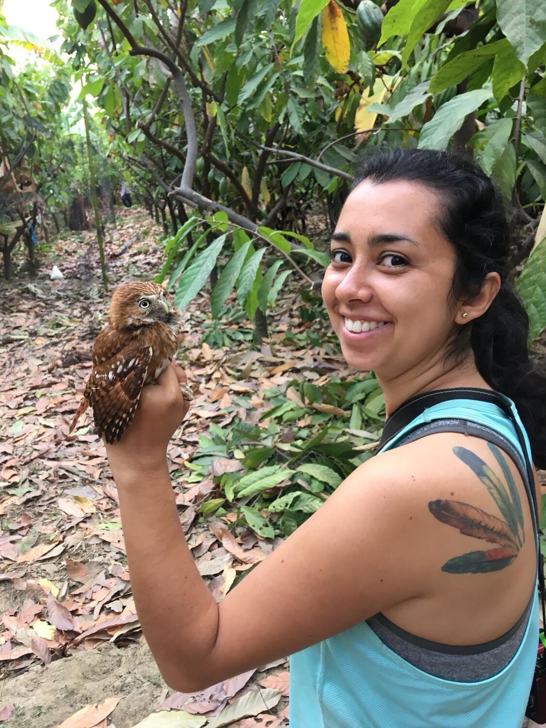 Carolina Ocampo-Ariza holding a Peruvian pygmy owl (Glaucidium peruanum) inside a cacao farm.